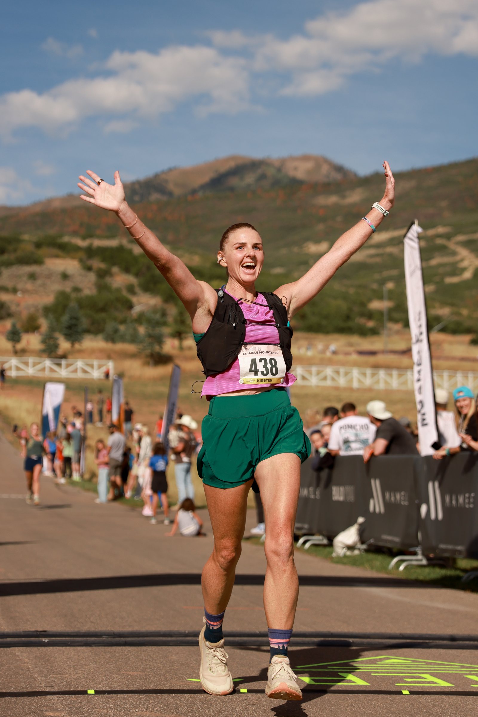A finisher coming through the arch with her arms thrown wide.
