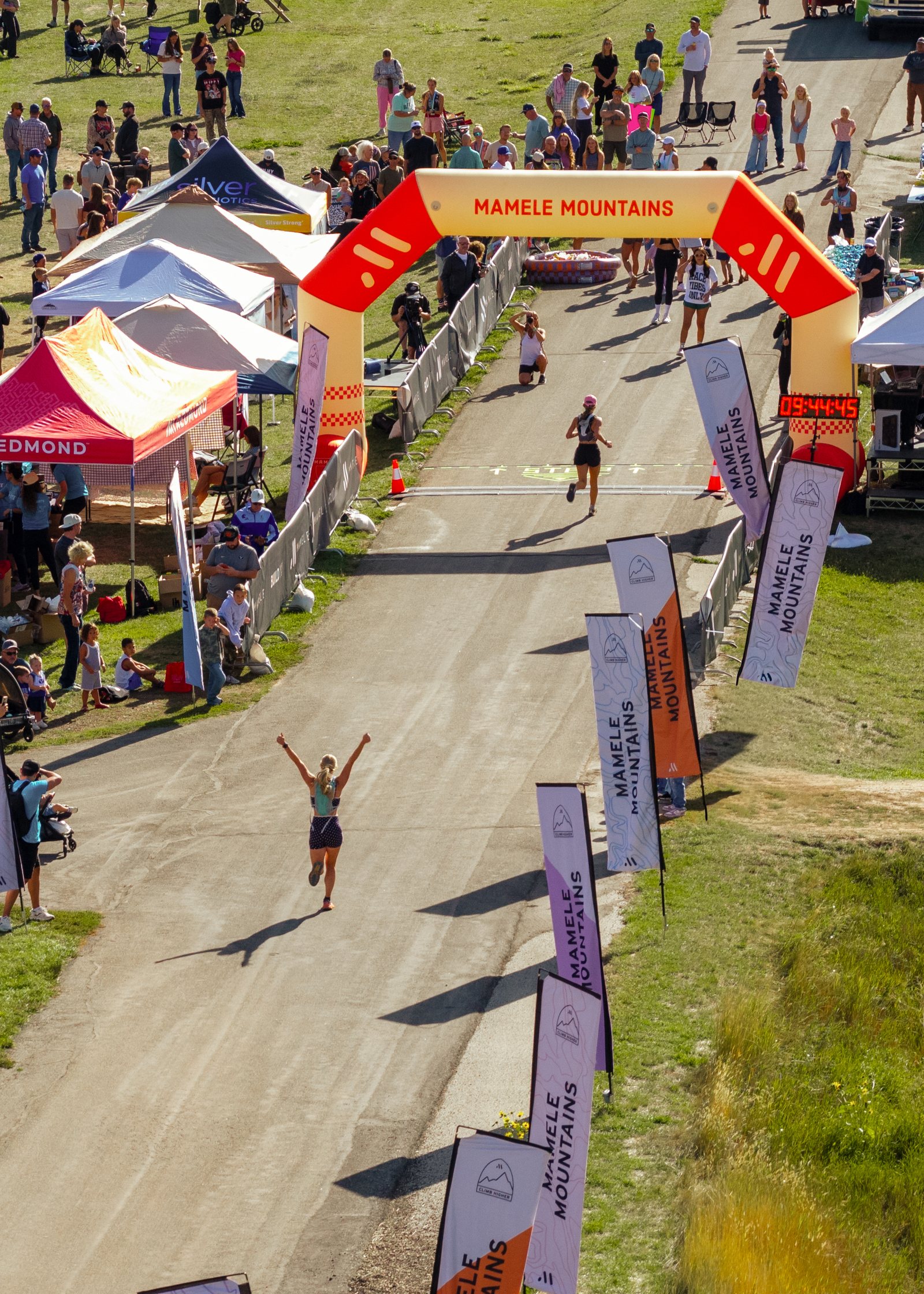 Overhead of the Mamele Mountains finish arch as a racer crosses with both arms raised.