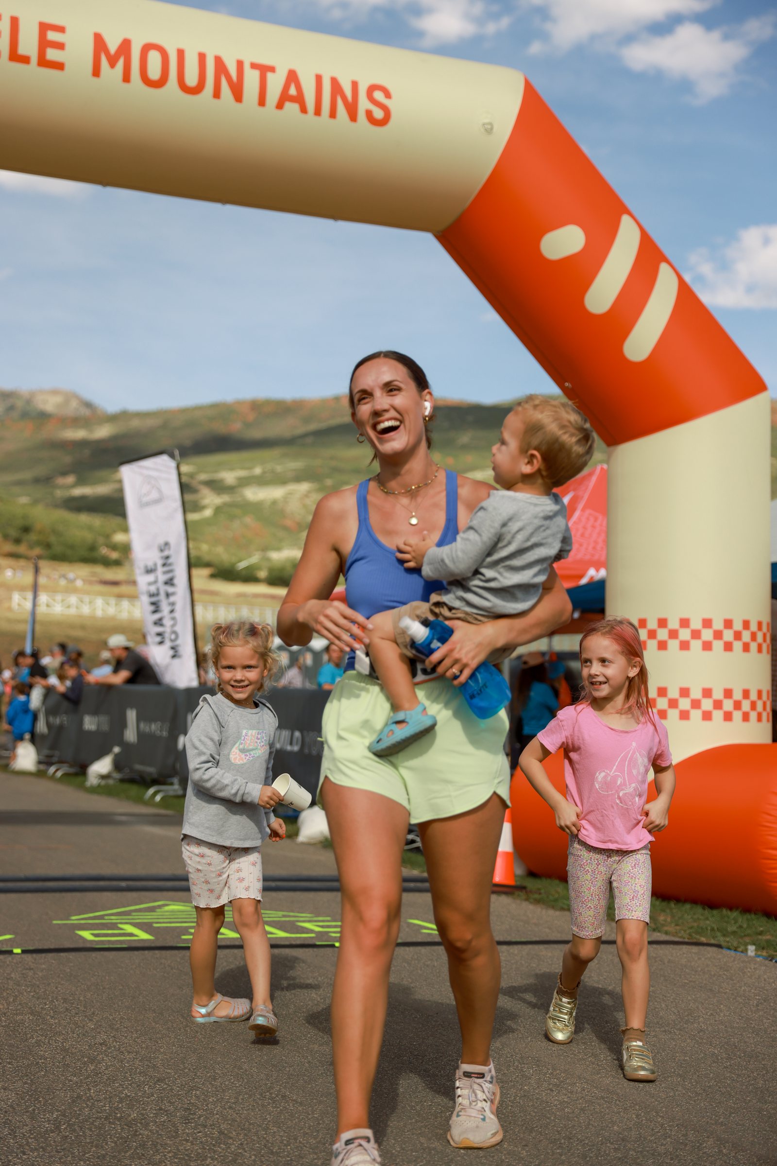 A mother finishing the race with her small child running beside her.