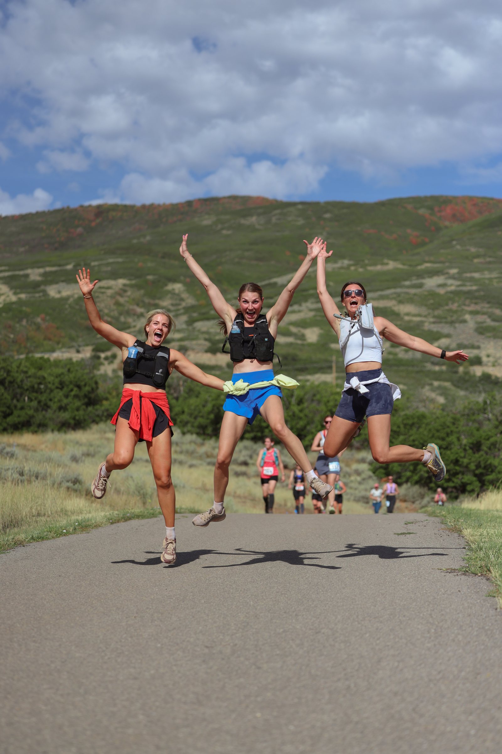 Three women jumping in the air together on the trail.
